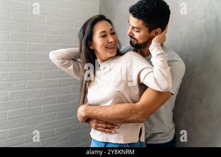 La bella coppia multietnica passa del tempo insieme, abbracciando e sorridendo Foto Stock