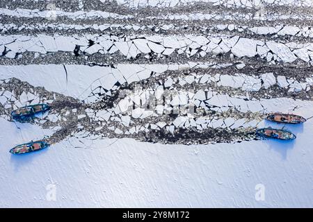 Quattro rompighiaccio che tritano ghiaccio sul fiume. Veduta aerea della natura in inverno. Veduta aerea della natura in inverno Foto Stock