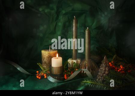 Primo Avvento, quattro candele, una accesa, ramoscelli, bacche rosse, nastro e decorazioni natalizie di fronte a uno sfondo verde scuro, abbottonatura natalizia Foto Stock