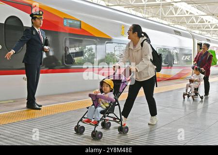 YANTAI, CINA - 6 OTTOBRE 2024 - Un membro del personale del treno guida i passeggeri a bordo di un treno alla stazione di Yantai nella provincia di Shandong nella Cina orientale, il 6 ottobre, Foto Stock