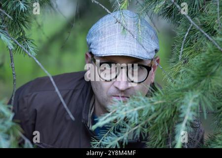 Uno stalker inquietante che si nasconde tra le piante guarda nella telecamera. Foto Stock