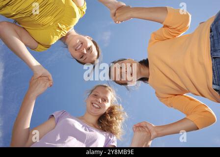 Un gruppo di tre amici sorridenti con la testa che guardano insieme la fotocamera. Vista ad angolo basso Foto Stock