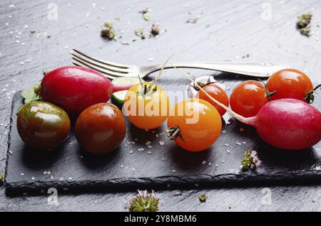 Fresche verdure organiche su pietra ardesia vassoio con spezie da parte closeup concetto scuro foto Foto Stock