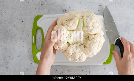 Lo chef ha trasformato il cavolfiore in fiori, il processo di cottura, vista dall'alto. Ricetta per cavolfiore arrostito al forno. Foto Stock