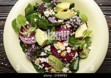 Vista superiore al mediterraneo barbabietole arrosto con insalata di avocado noci e formaggio feta origano e mash lascia sul tavolo di legno Foto Stock