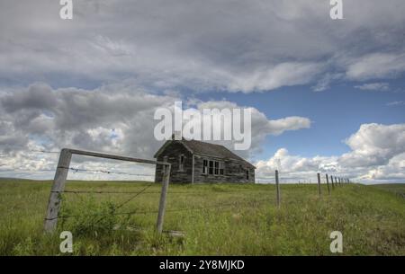 Azienda abbandonata con nuvole temporalesche nella prateria canadese Foto Stock
