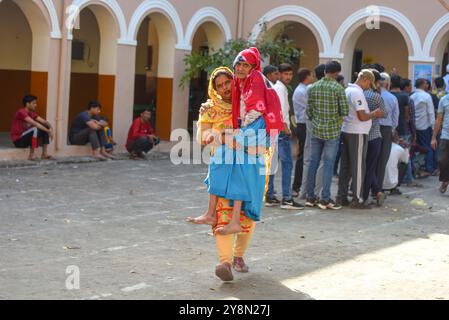 GURUGRAM, INDIA - 5 OTTOBRE: Pooja che porta in grembo la suocera di 92 anni per esprimere il loro voto per l'elezione dell'Assemblea Haryana alla scuola superiore pubblica Shiv a Sohna, il 5 ottobre 2024 a Gurugram, India. Un totale di 1.031 candidati si contestano in tutte le 90 circoscrizioni elettorali, e sono state istituite 20.632 cabine elettorali per il voto. Un totale di 2, 03, 54.350 elettori nello stato saranno in grado di esercitare i loro diritti nelle elezioni della 15a Assemblea legislativa di Haryana. (Foto di Parveen Kumar/Hindustan Times/Sipa USA ) Foto Stock