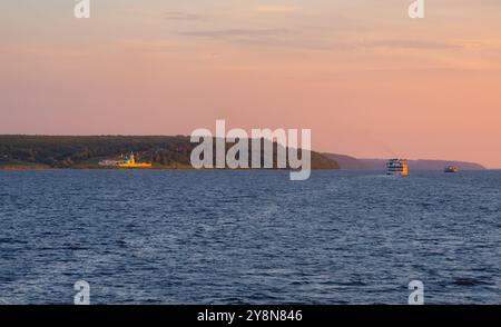 Un piroscafo turistico naviga oltre la Chiesa dell'Intercessione della Beata Vergine Maria sulle rive del fiume Volga durante il tramonto Foto Stock