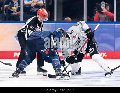 Linesperson David Tschirner fuehrt ein bully aus zwischen Adam Brooks (EHC Red Bull Muenchen, n. 77) e Josh Currie (Koelner Haie, n. 18). GER, EHC Red Bull Muenchen gegen Koelner Haie, Eishockey, DEL, 7. Spieltag, Saison 2024/2025, 06.10.2024. Foto: Eibner-Pressefoto/Franz Feiner Foto Stock