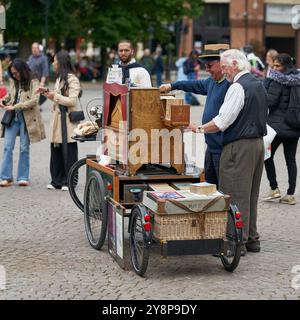 Un trituratore di organi e un curioso turista che parla sulla piazza Burg, de Burg a Bruges, in Belgio Foto Stock