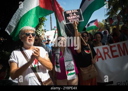 Malaga, Spagna. 6 ottobre 2024. Un manifestante tiene un cartello durante una manifestazione globale contro il genocidio in Palestina a seguito dell'escalation del conflitto in Medio Oriente. Un giorno prima dell'anniversario degli attentati del 7 ottobre e dell'inizio della guerra tra Israele e Hamas, migliaia di persone si recano per le strade della città di Malaga in solidarietà con il Libano e la Palestina per chiedere la fine del commercio di armi con Israele e dell'occupazione militare israeliana in Palestina. Credito: SOPA Images Limited/Alamy Live News Foto Stock