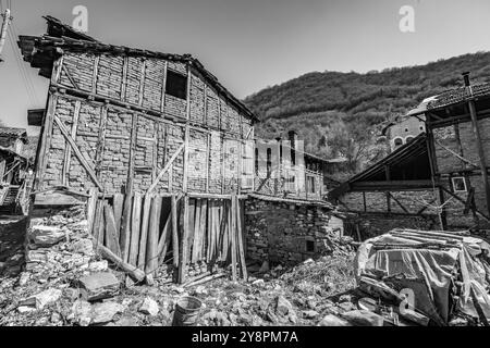 Case abbandonate e altri edifici, illuminati dalla luce del sole, vista sulla strada, villaggio di Pirin e montagna, Bulgaria Foto Stock