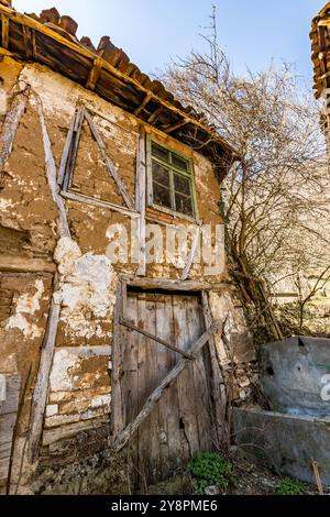 Case abbandonate e altri edifici, illuminati dalla luce del sole, vista sulla strada, villaggio di Pirin e montagna, Bulgaria Foto Stock