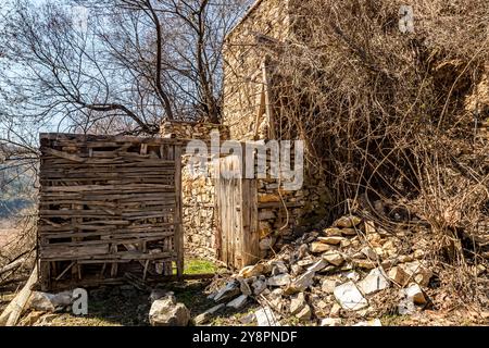 Case abbandonate e altri edifici, illuminati dalla luce del sole, vista sulla strada, villaggio di Pirin e montagna, Bulgaria Foto Stock