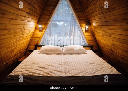 Accogliente camera in legno con letto grande e luce naturale, a creare un'atmosfera calda e invitante Foto Stock