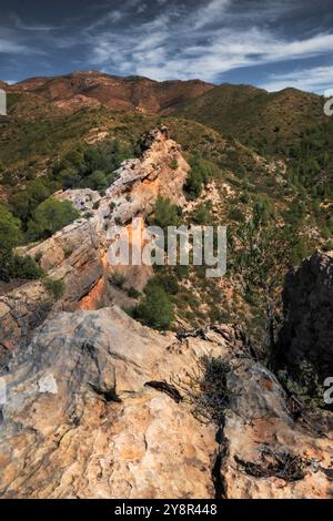 Un paesaggio roccioso di scogliera che si affaccia su una lussureggiante valle verde e un'ampia vista del cielo Foto Stock