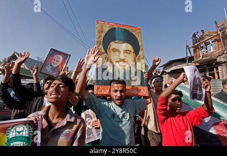 Pattan, Kashmir, India. 6 ottobre 2024. i musulmani sciiti del Kashmir portano foto del leader di Hezbollah Hassan Nasralla e gridano slogan anti Israele mentre prendono parte a una manifestazione per mostrare la loro rabbia verso l'uccisione del leader di Hezbollah Hassan Nasrallah. Nasrallah fu ucciso nei sobborghi meridionali di Beirut, in Libano, da un attacco aereo israeliano. Foto Stock