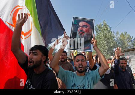 Pattan, Kashmir, India. 6 ottobre 2024. i musulmani sciiti del Kashmir portano foto del leader di Hezbollah Hassan Nasralla e gridano slogan anti Israele mentre prendono parte a una manifestazione per mostrare la loro rabbia verso l'uccisione del leader di Hezbollah Hassan Nasrallah. Nasrallah fu ucciso nei sobborghi meridionali di Beirut, in Libano, da un attacco aereo israeliano. Foto Stock