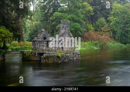 Incantevole casa di pescatori di pietra Monk sul fiume Cong a Cong Abbey, in Irlanda, in una giornata di pioggia Foto Stock