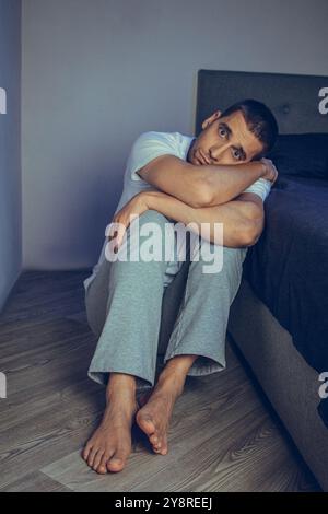 Ritratto drammatico di uno stile di vita di un bel ragazzo di 30 e 40 anni, seduto tristemente sul letto, sentendosi ansioso e soffrendo di depressione. Attraente Foto Stock