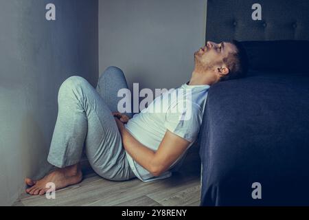 Ritratto drammatico di uno stile di vita di un bel ragazzo di 30 e 40 anni, seduto tristemente sul letto, sentendosi ansioso e soffrendo di depressione. Attraente Foto Stock