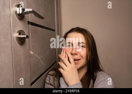 La ragazza sta tenendo un filo per tirare fuori un dente. Estrazione di un dente in un adulto. Cure dentistiche. Il concetto di mal di denti, problemi con i denti Foto Stock