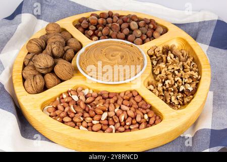 Arachidi, noci e nocciole in una scatola di legno con scomparti. Tre diversi tipi di dadi, con guscio e guscio, assortimento decorativo e pronti all'uso Foto Stock