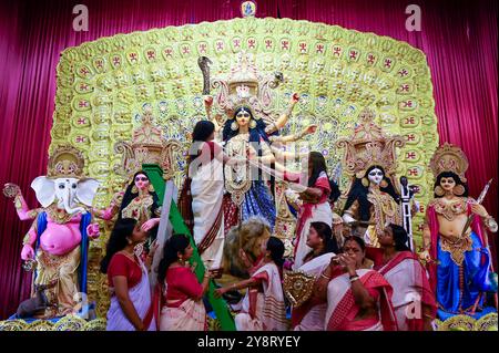 Kolkata, India. 6 ottobre 2024. KOLKATA, INDIA - 5 OTTOBRE: Donne in abito tradizionale che mettono dieci armi in un idolo della divinità indù Dea Durga per mano a Dharma Prasarini Samiti di Mukherjee Ghat Pandal, il 5 ottobre 2024 a Kolkata, India. (Foto di Samir Jana/Hindustan Times/Sipa USA ) credito: SIPA USA/Alamy Live News Foto Stock