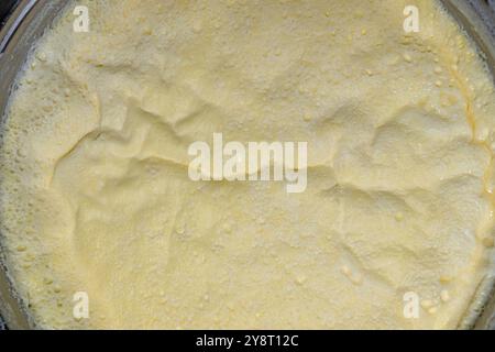 Uno strato di panna formato sul latte bollito in una pentola. Primo piano. Foto Stock