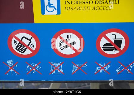 Un cartello ufficiale d'ingresso al Vaticano a Roma, in Italia, che mostra informazioni di accesso per disabili e icone di oggetti proibiti per i pellegrini in visita. Foto Stock