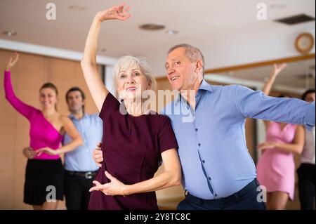 Allegra coppia anziana che pratica danze da ballo nella sala da ballo Foto Stock