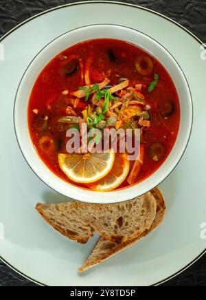 La zuppa di Solyanka viene servita in un recipiente bianco con pane di segale Foto Stock