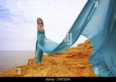 Giovane bella donna in vestito blu gode di giornata di sole al mare Foto Stock