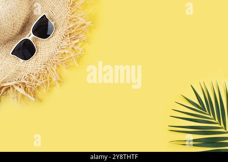 Pianificazione di viaggi in vacanza semplice tema di cappello di paglia occhiali da sole e foglie di palma su sfondo giallo uniforme, piatto con spazio per copia Foto Stock