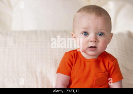 Un ragazzo si siede sul letto guardando sorpreso Foto Stock