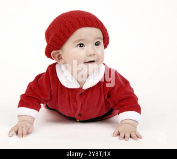 Carino Infant Boy in una composizione orizzontale strisciando nel vestito rosso e hat Foto Stock