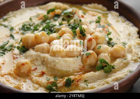 Vista sul closeup all'Hummus sormontato da olio di oliva di fagioli e foglie di coriandolo verde sul tavolo da cucina Foto Stock