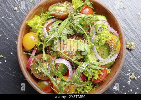 Vista superiore in insalata di verdure di lattuga, pomodori ciliegini, rafano, cetriolo, cipolla e basilico sul vassoio di ardesia Foto Stock
