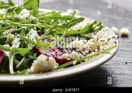 Piatto di argilla con barbabietole rosse foglie di rucola e formaggio feta insalata su pietra ardesia vassoio vista ingrandita Foto Stock