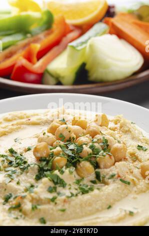 Vista a basso angolo su piatto di verdure con hummus condito con ceci e olio d'oliva Foto Stock