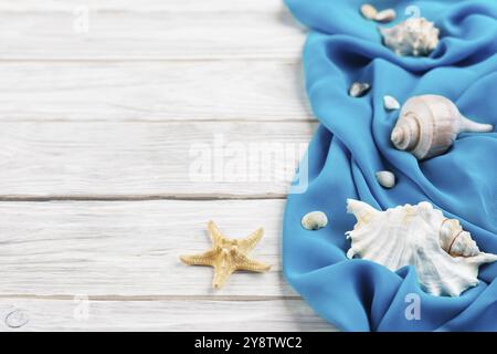 Conchiglie, tessuto blu e stelle marine su tavole bianche sfondo piano per la pianificazione delle vacanze con spazio per copie Foto Stock