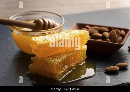 Vassoio di ardesia con mandorle al miele e nido d'ape sul tavolo da cucina Foto Stock