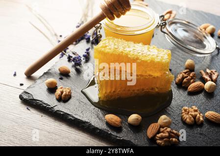 Nido d'ape su vassoio di ardesia con miele e noci sul tavolo da cucina Foto Stock