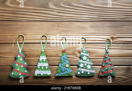 Rustico fatte a mano feltro verde albero di Natale decorazioni che giace piatto su un tavolo di legno Foto Stock