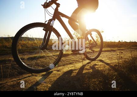 Ciclista maschio la guida da rurale strada sterrata all'esterno. Basso angolo di visione Foto Stock