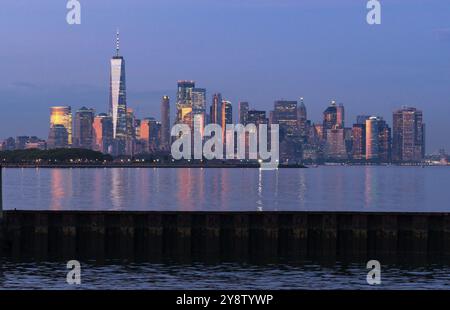 La luce del tramonto si riflette gli edifici sulla Baia di Hudson al tramonto a Manhattan Foto Stock