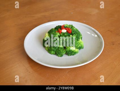 broccoli verdi brasati freschi con pepe rosso piccante sul piatto bianco Foto Stock