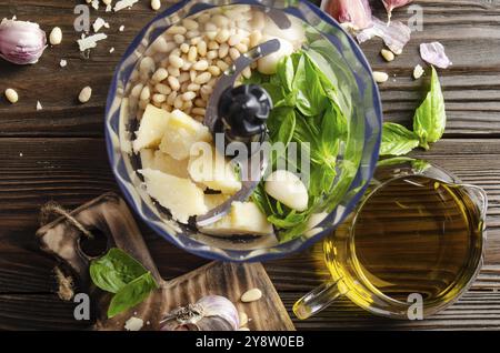 Ingredienti per la tradizionale salsa di pesto genovese italiana nel recipiente del robot da cucina. Vista piatta Foto Stock