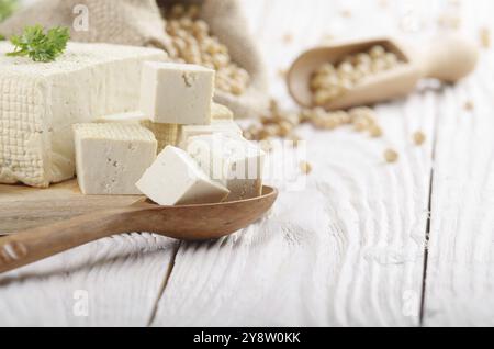 Fagiolo di soia tofu cagliata sul tagliere e nel sacco di canapa su bianco cucina in legno tavolo. Spazio per il testo Foto Stock