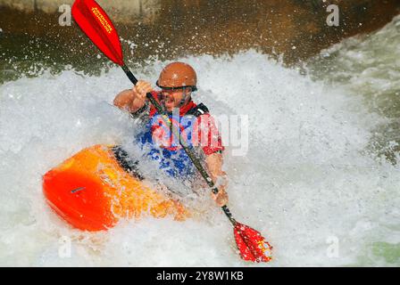 Un uomo adulto pratica le sue abilità di kayak in rapide rapide allo US Whitewater Center di Charlotte, North Carolina; Foto Stock